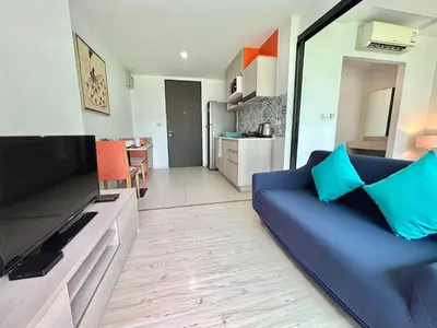 a living room with a blue couch and a kitchen at 1 Bedroom Condos Close to Shopping Malls in Ban Rangeng