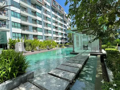 a swimming pool in front of a large building at 1 Bedroom Condos Close to Shopping Malls in Ban Rangeng