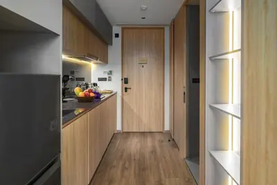 a hallway leading to a kitchen with a wooden door at Amazing La Green 10 min walk to Layan Beach in Layan Beach