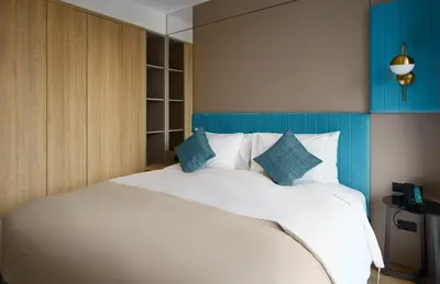 a bedroom with a large white bed with blue accents at Amazing La Green 10 min walk to Layan Beach in Layan Beach