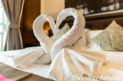 two towel swans making a heart on a bed at OMNIAPHUKET - Pool View Apartment at Phuket Villa Patong Beach in Patong Beach