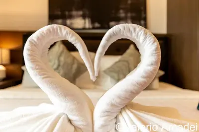 two swans forming a heart in front of a bed at OMNIAPHUKET - Pool View Apartment at Phuket Villa Patong Beach in Patong Beach