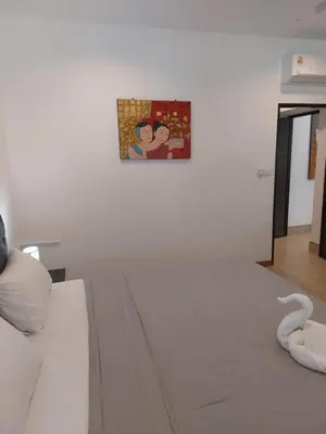 a white bed in a room with a picture on the wall at Smile House Apartment 24 in Karon Beach