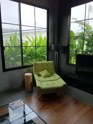 a living room with a green chair and windows at New 2 BR Villa Nai Thon in Nai Yang Beach