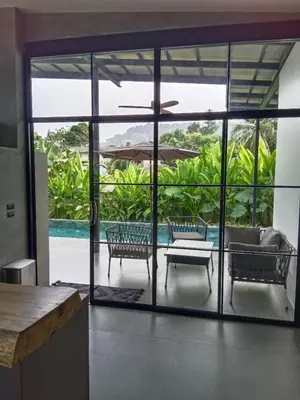 a living room with sliding glass doors leading to a patio at New 2 BR Villa Nai Thon in Nai Yang Beach