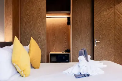 a hotel room with a bed with yellow pillows at Suite Edena 2BR Pool View 300m to Rawai in Rawai Beach