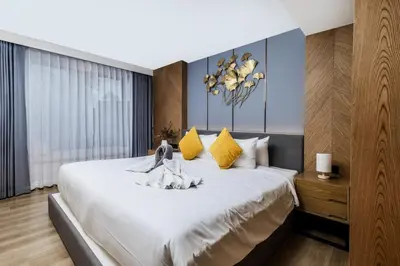 a bedroom with a large white bed with yellow pillows at Suite Edena 2BR Pool View 300m to Rawai in Rawai Beach