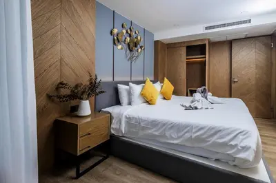 a bedroom with a large white bed with yellow pillows at Suite Edena 2BR Pool View 300m to Rawai in Rawai Beach