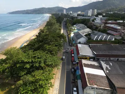 a view of a beach with a train on a road at Bed & Beach Hostel Karon in Karon Beach