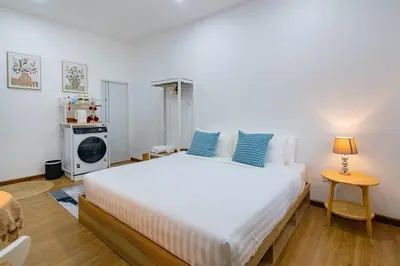 a bedroom with a large white bed with blue pillows at Sachi Minimal House Bangtao Beach - Near Muay Thai Gym in Surin Beach
