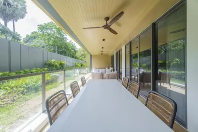 a long table with chairs and a ceiling fan at Laguna Beachfront 3BR Cozy Condo in Bang Tao Beach