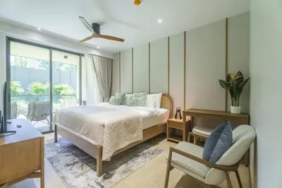 a bedroom with a bed and a chair at Laguna Beachfront 3BR Cozy Condo in Bang Tao Beach