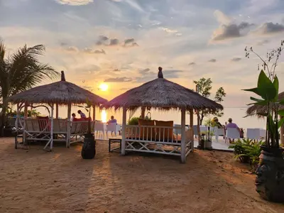 a couple of gazebos on a beach with the sunset at Krabi Sea View Orchid Beach room in Krabi town