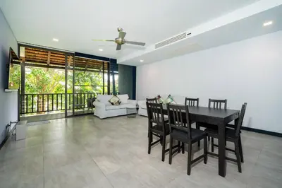 a dining room with a table and chairs and a couch at Bangtao Beach Garden - 2 BR Apartment in Surin Beach
