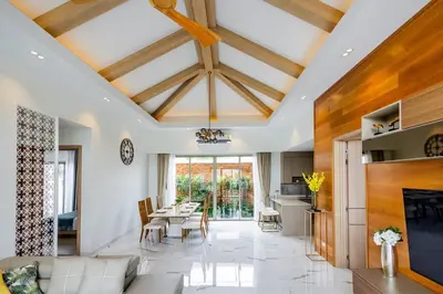 a dining room and living room with a ceiling with beams at Khanaen Luxury Pool Villa by SP in Ban Chin Tham Mai
