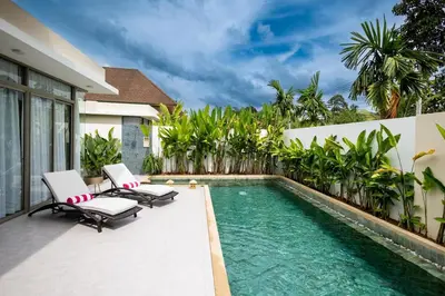 a swimming pool with two lounge chairs next to a house at Khanaen Luxury Pool Villa by SP in Ban Chin Tham Mai