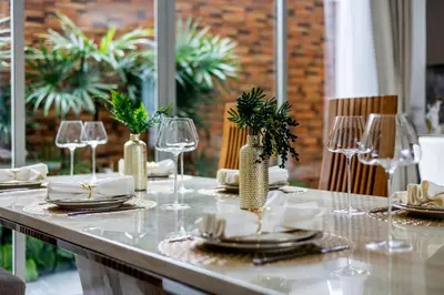 a table with wine glasses and plates on it at Khanaen Luxury Pool Villa by SP in Ban Chin Tham Mai