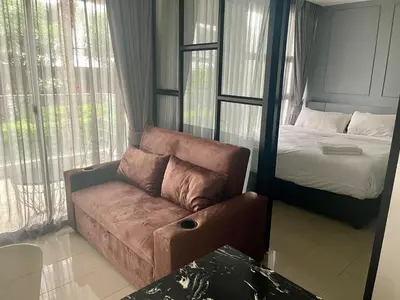 a living room with a couch and a bed at The Palmirah Surin by SP in Surin Beach