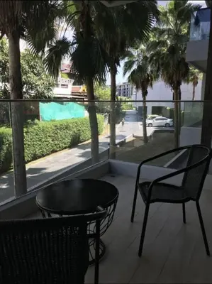 a balcony with a table and chairs and a view of a street at The Palmirah Surin by SP in Surin Beach