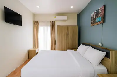 a bedroom with a white bed and a television at Sundiva Guest House in Patong Beach