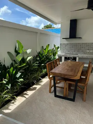 a wooden table and chairs on a patio with plants at Chalong Home Phuket in Phuket Town