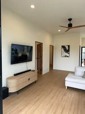 a living room with a couch and a tv on the wall at Chalong Home Phuket in Phuket Town