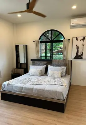 a bedroom with a large bed and a window at Chalong Home Phuket in Phuket Town