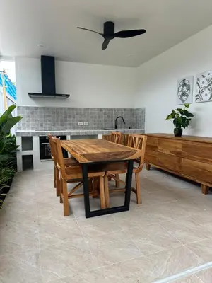 a kitchen with a wooden table and wooden chairs at Chalong Home Phuket in Phuket Town