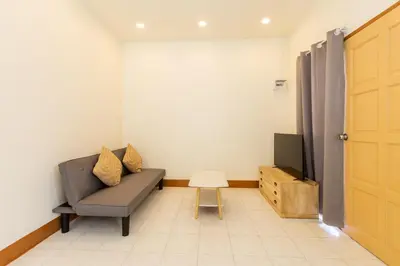 a living room with a couch and a television at Homehug in Ban Thalat Choeng Thale
