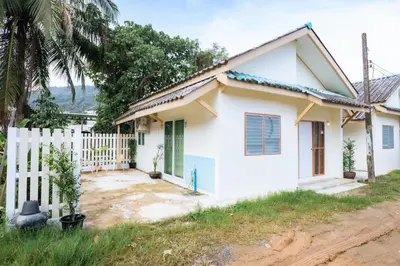 a white house with a white fence at Homehug in Ban Thalat Choeng Thale