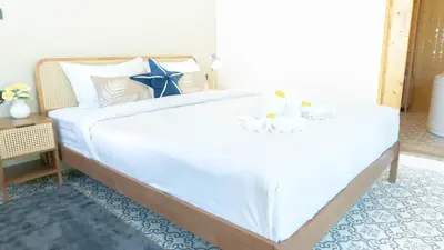 a bedroom with a large white bed with white and blue pillows at Jaokhun Hilltop Patong, Phuket in Patong Beach