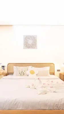 a white bed with white sheets and pink flowers on it at Jaokhun Hilltop Patong, Phuket in Patong Beach