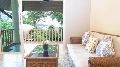 a living room with a couch and a glass table at Jaokhun Hilltop Patong, Phuket in Patong Beach