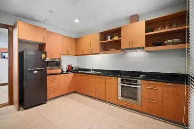 a kitchen with wooden cabinets and a black refrigerator at Laguna Village 2 Bedroom Pool View Villa by Banyan Living in Layan Beach