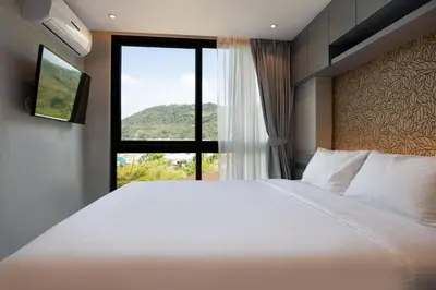 a bedroom with a large white bed and a window at Tropical Kamala Hill View 1 BR CTG P407 in Kamala Beach