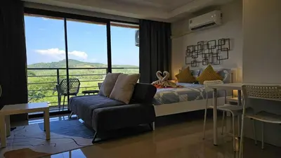 a bedroom with a bed and a couch and a balcony at Квартира in Ban Mai Salae