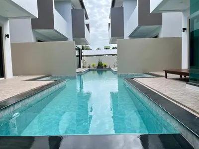 a swimming pool in a house with blue water at Bay Sand Villa by Jai House Phuket in Ban Klang