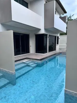 a swimming pool in front of a house at Bay Sand Villa by Jai House Phuket in Ban Klang