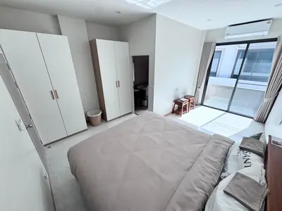 a bedroom with a large bed and a large window at Bay Sand Villa by Jai House Phuket in Ban Klang