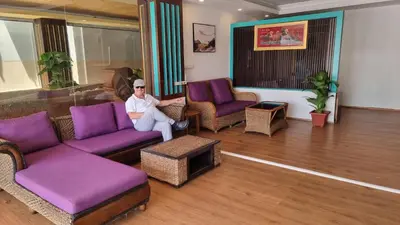 a man sitting in a living room with purple furniture at Sereneburi Patong Hotel in Patong Beach