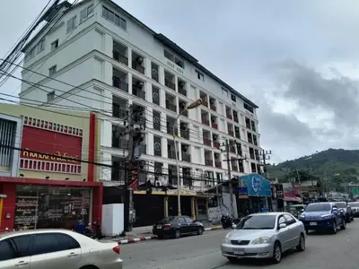 a large white building on a city street with cars at Sereneburi Patong Hotel in Patong Beach