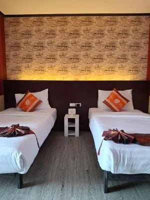two beds in a room with a wall at Sereneburi Patong Hotel in Patong Beach
