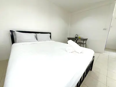 a bedroom with two beds with white sheets and a table at Patong Canal Villa 108 in Patong Beach