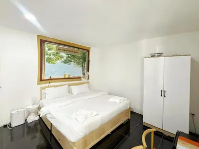 a white bedroom with a bed and a window at \u82ad\u4e1c\u6d77\u6ee9\u5fc3\u6f84\u9152\u5e97 in Patong Beach