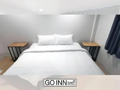a bed in a room with two tables at GO INN Phuket Old Town - โกอินน์ ภูเก็ต โอลทาวน์ in Phuket Town