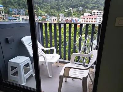 two white chairs and a stool on a balcony at The Deck Condo Patong Mountain View1 in Patong Beach