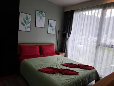 a bedroom with a bed with red sheets and a window at The Deck Condo Patong Mountain View1 in Patong Beach