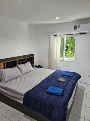 a bedroom with a bed with blue sheets and a window at Bestin Karon 2 in Karon Beach