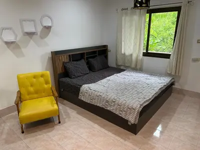 a bedroom with a bed and a yellow chair at Bestin Karon 2 in Karon Beach