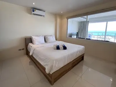 a bedroom with a large bed with a window at Sunset Plaza Karon Seaview in Karon Beach